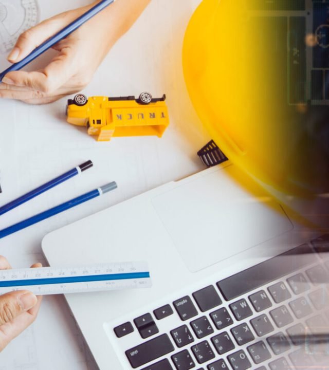 Two colleagues discussing data working and tablet, laptop with on on architectural project at construction site at desk in office